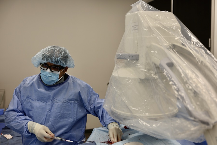 Dr. Samy Al-Bayati guiding a catheter with a syringe during a hemorrhoid artery embolization at ARV Centers